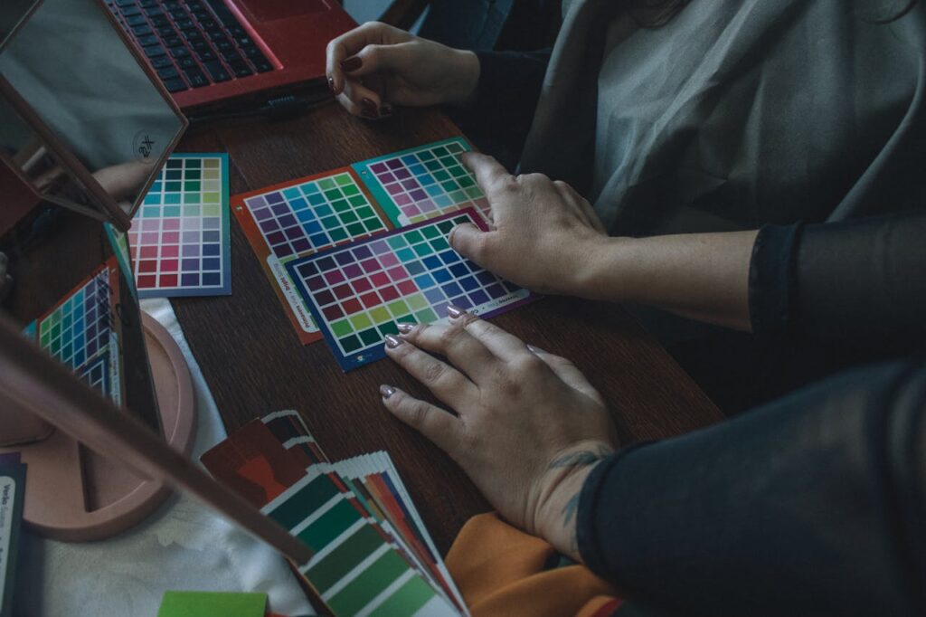 Close-up of hands choosing color palettes on a desk with vibrant swatches.